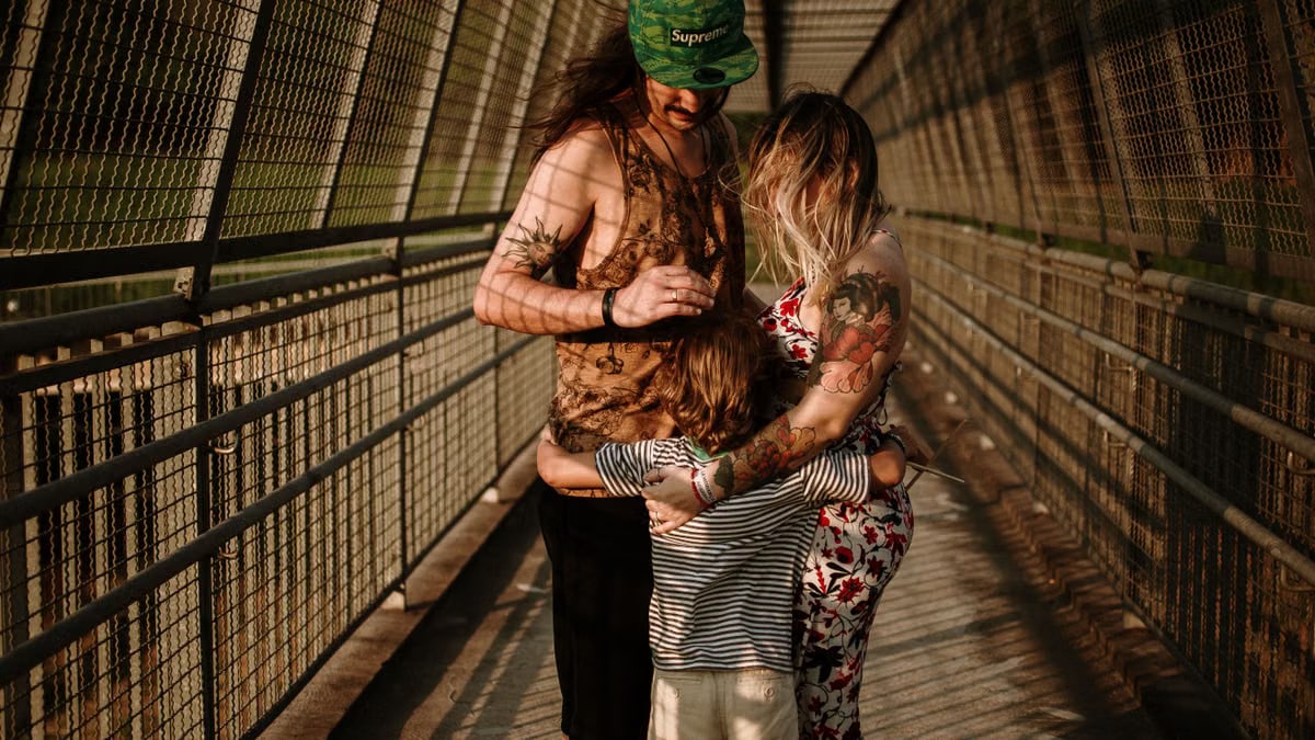 A family embracing on a sunlit bridge, capturing warmth and togetherness.